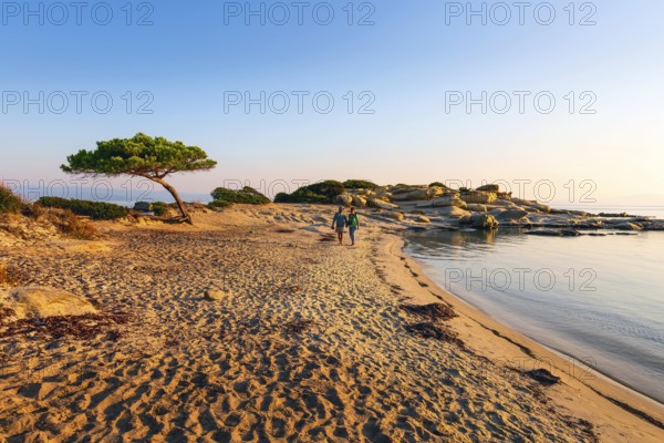 Vourvourou, Sithonia, Greece, September 17, 2019: Couple walking at sunrise Karidi beach.