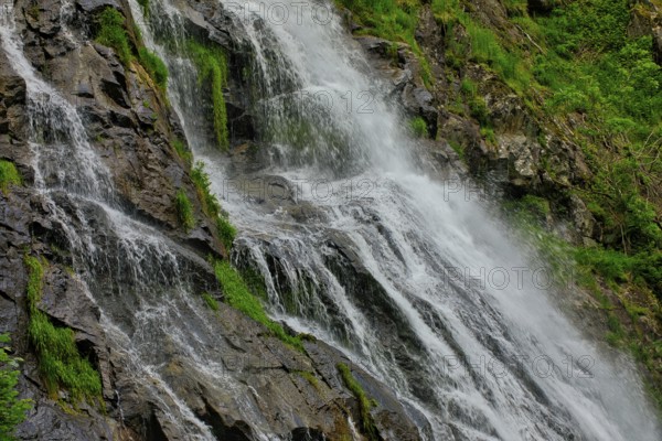 Close-up of a waterfall flowing over moss-covered rocks and conveying freshness, waterfall,