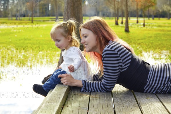 Daughter and mother playing together in the park lake pier