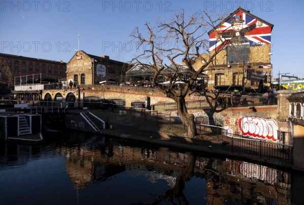 A beautiful canal scene with a building adorned with a British flag, a leafless tree, and