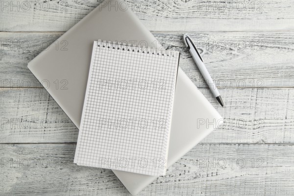 White paper Notepad and laptop on vintage shabby white wooden background. the view from the top.
