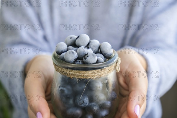 Woman holding bowl with Frozen blueberry fruits. Harvesting concept. Female hands collecting