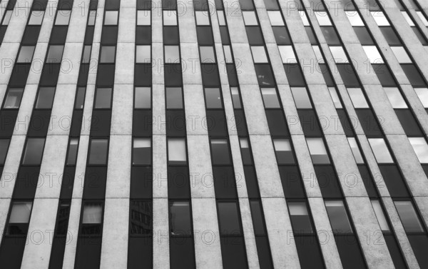 Close up perspective detail of tall high rise brutalist style office building with white vertical
