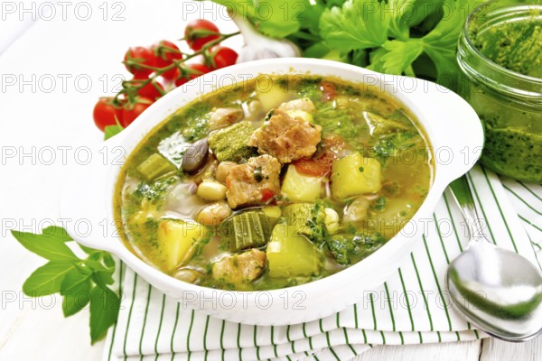 Soup with pisto sauce, pork fat, tomatoes, zucchini, beans, celery and leek in a bowl on a towel on