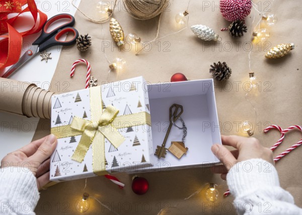 Key to house with keychain on cozy home in gift box with Christmas decor packaging. Pack present