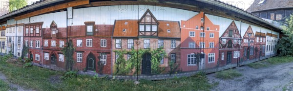 Panoramic photo of garage doors, with graffiti facades of buildings from the medieval old town of