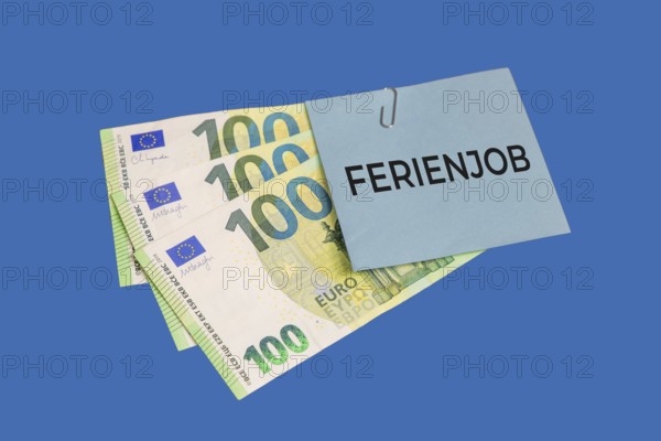 Holiday job symbol image: euro banknotes and a piece of paper with the words HOLIDAY JOB cut out