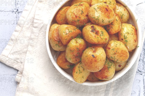 Baked new potatoes, with butter and dill, on a white plate, at home, no people