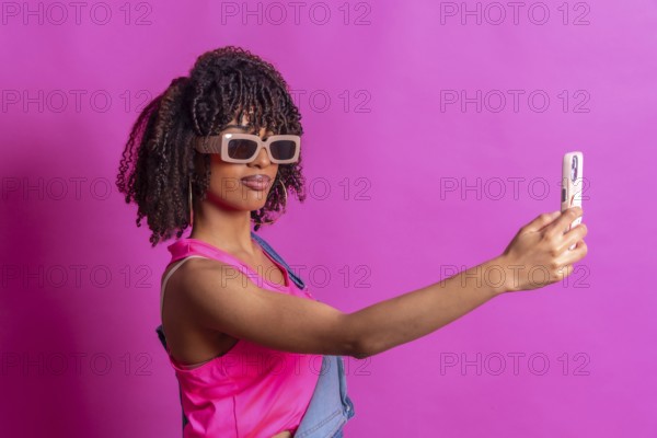 Fashionable young woman taking a selfie with smartphone, wearing sunglasses and pink top on a