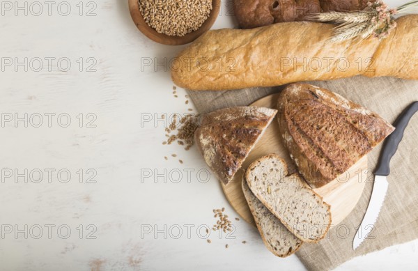 Sliced bread with different kinds of fresh baked bread on a white wooden background. top view, flat