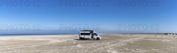 Ringby, Denmark: 31 May, 2021: panorama of a gray camper van parked on an endless white sand beach