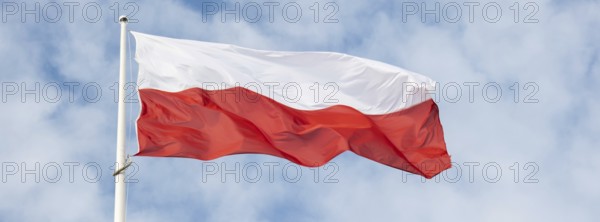 Flag of Poland waving at wind against beautiful blue sky. Polish flag White and red flutters on