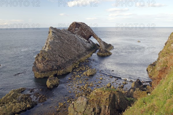 Rocky island by the sea with gentle waves surrounded by a clear sky, Bow Fiddle Rock,