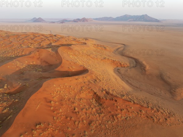 Sand dunes and isolated mountain ridges at the edge of the Namib Desert. Aerial view. Drone shot.