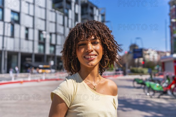 Smiling young woman enjoying a sunny summer day in a vibrant urban setting, surrounded by modern