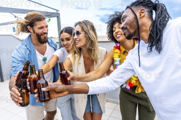 Happy friends celebrating on a rooftop, toasting with beer bottles and enjoying quality time