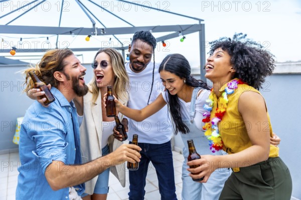 Cheerful multi ethnic friends are toasting with bottles of beer, laughing and having fun at a