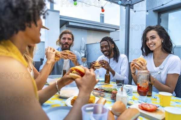 Cheerful multi ethnic friends savoring burgers and drinks while enjoying a lively rooftop barbecue