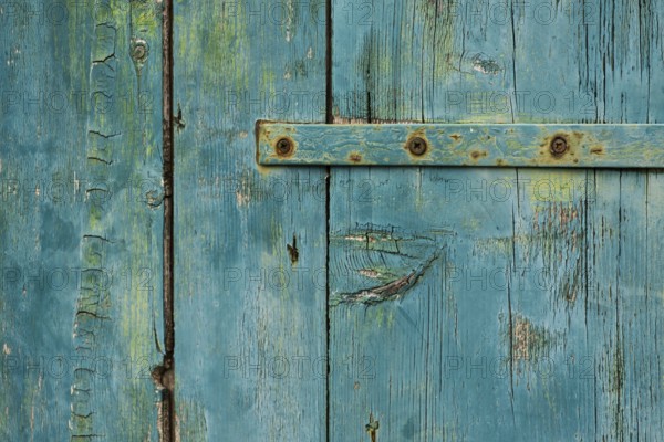 Weathered green wooden door with rusty metal accents in rustic style, background, texture,