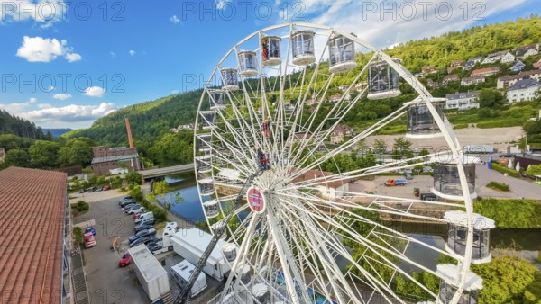 A Ferris wheel with lorries underneath, near a river in a green environment, fire brigade exercise