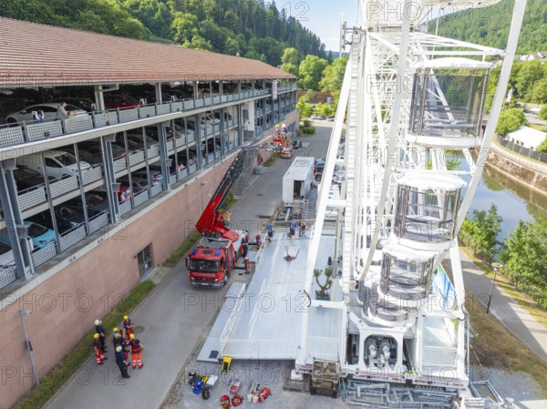 Fire engines and workers next to a Ferris wheel in an urban environment, fire brigade exercise for