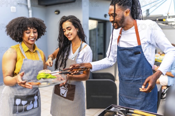 Happy multi ethnic friends preparing grilled vegetables and meat, enjoying barbecue party on the