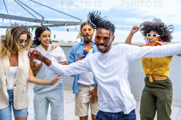 Young people dancing and singing joyfully at a vibrant rooftop party, enjoying music and