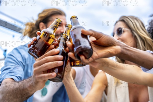 Group of friends celebrating on a rooftop, raising their beer bottles high for a joyful toast,
