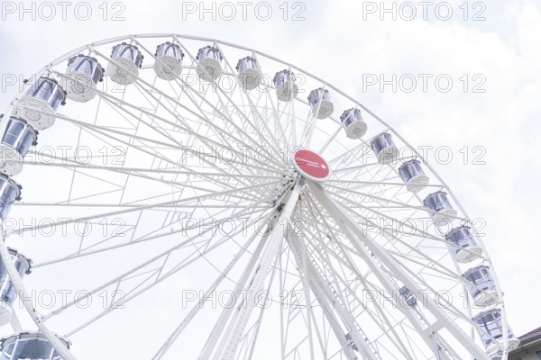 Large Ferris wheel with white gondolas and a sunny sky as a backdrop, Ferris wheel construction,