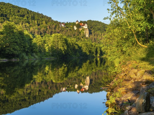 Prunn Castle on a steep cliff above the Altmühl Valley in the evening light, reflection in the
