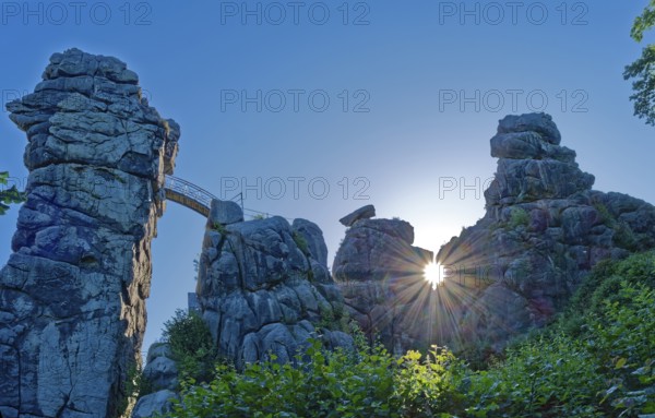 The morning sun shines through an opening in the Externsteine. The Externsteine, a sandstone rock