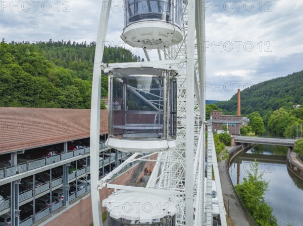 Ferris wheel with gondolas next to a building and a river, Ferris wheel construction for the 950th