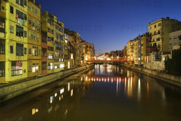 Girona city by night in Spain, waterside houses on the River Onyar, picturesque urban landscape in
