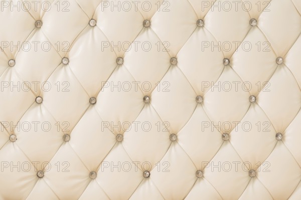 Beige soft tapestry pattern background with symmetrical buttons on the corners of diamonds. Soft