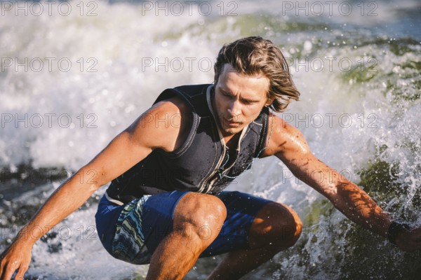 A man is surfing on a surfboard drawn by a motor boat above the wave of the boat. Weixerfer is