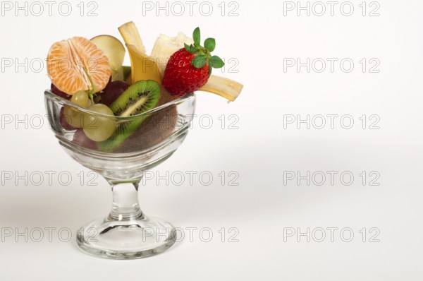 Fruit salad in a glass bowl on white background