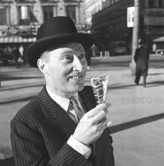 Ice cream in the 1960s. A well dressed gentleman in a suit and hat enjoys a ice cream on a sunny