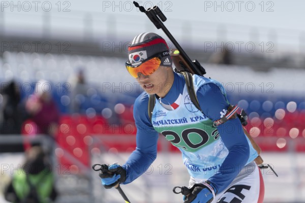 Sportsman biathlete Cheon Yunpil South Korea in action skiing on ski track distance biathlon arena.