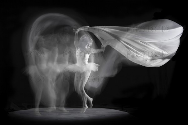 Ballerina in motion with flowing fabric, elegant and graceful in an artistic image, long exposure,