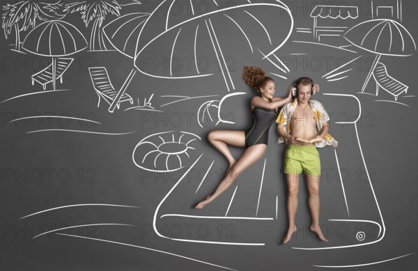 Love story concept of a romantic couple lying on an air mattress against chalk drawings background.