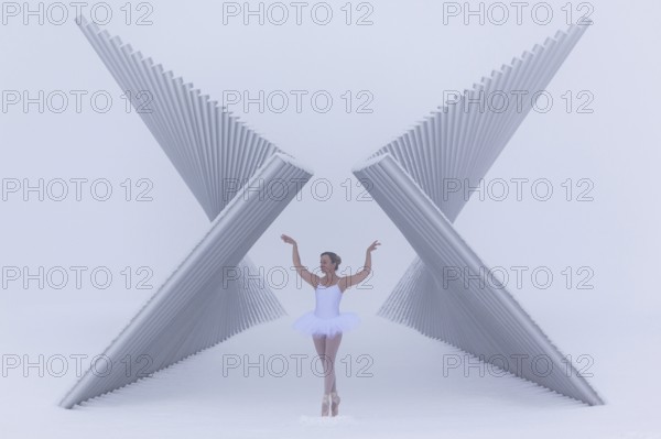 Ballerina poses gracefully between a futuristic sculpture in winter in sub-zero temperatures,