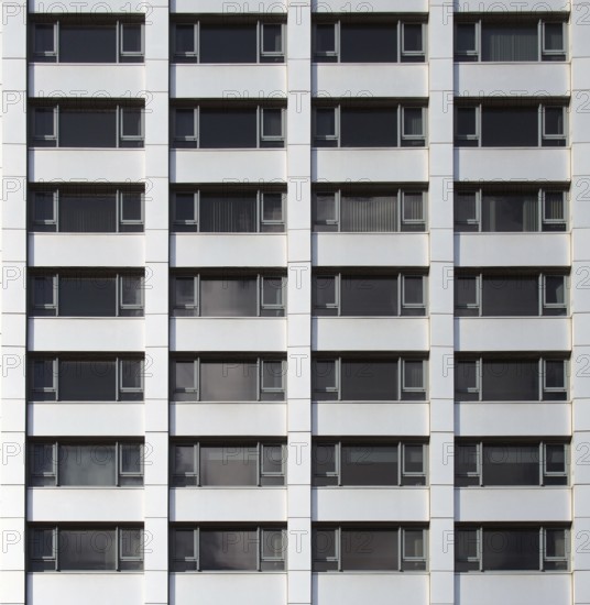 Front view of the facade of a modern commercial building with geometric repeating windows and grey