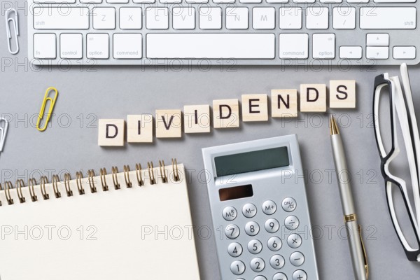 Dividends payment concept with letters on wooden cubes. Still life of office workplace with