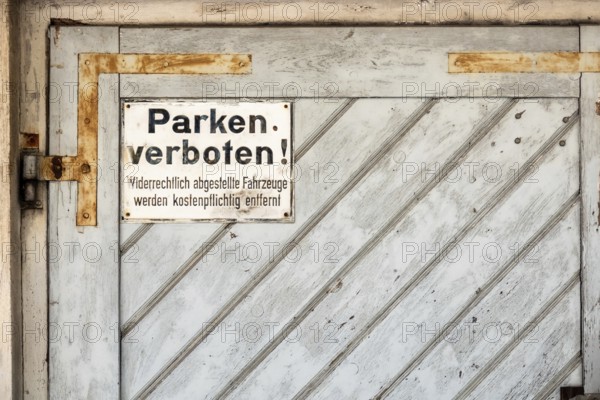 An image of a private no parking sign with german text Illegally parked vehicles will be towed at