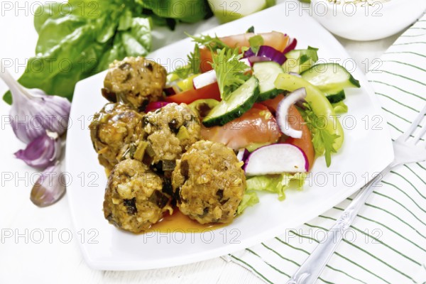 Minced meatballs with spinach, oatmeal and green onions in tomato sauce, vegetable salad in a