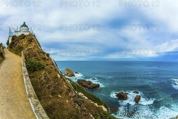 The white building of the lighthouse looks spectacular on a high cape. New Zealand. Nugget Point