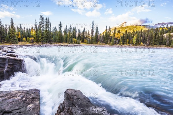 The full-water bubbling waterfall of Athabasca. Clear autumn evening in Canada. Cold blue water at