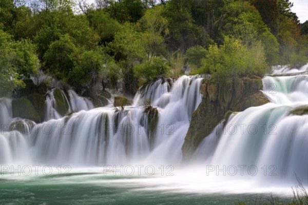A large waterfall flowing powerfully through trees and rocks, Krka National Park, Krka Waterfalls,