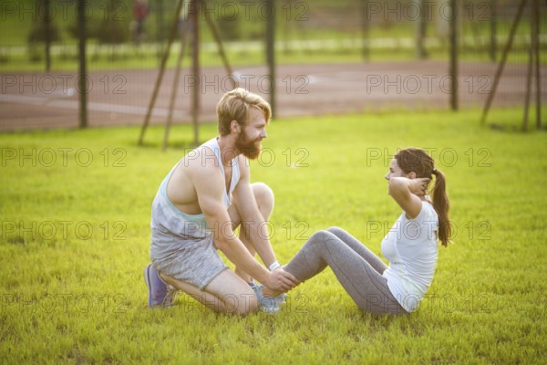 Sit ups fitness couple exercising sit up outside in graß Fit people working out cross training.