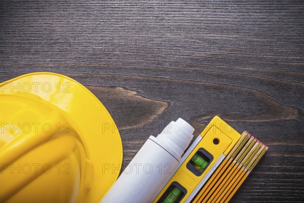 Horizontal view of blueprint roll construction level building helmet and wooden meter on vintage